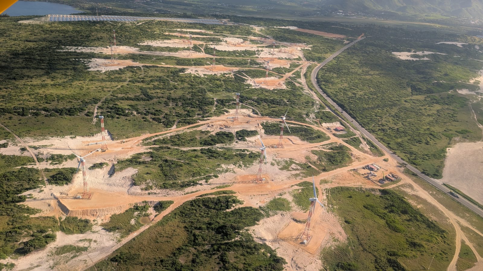 Vue aérienne chantier éolien avec grues et routes d'accès rurales