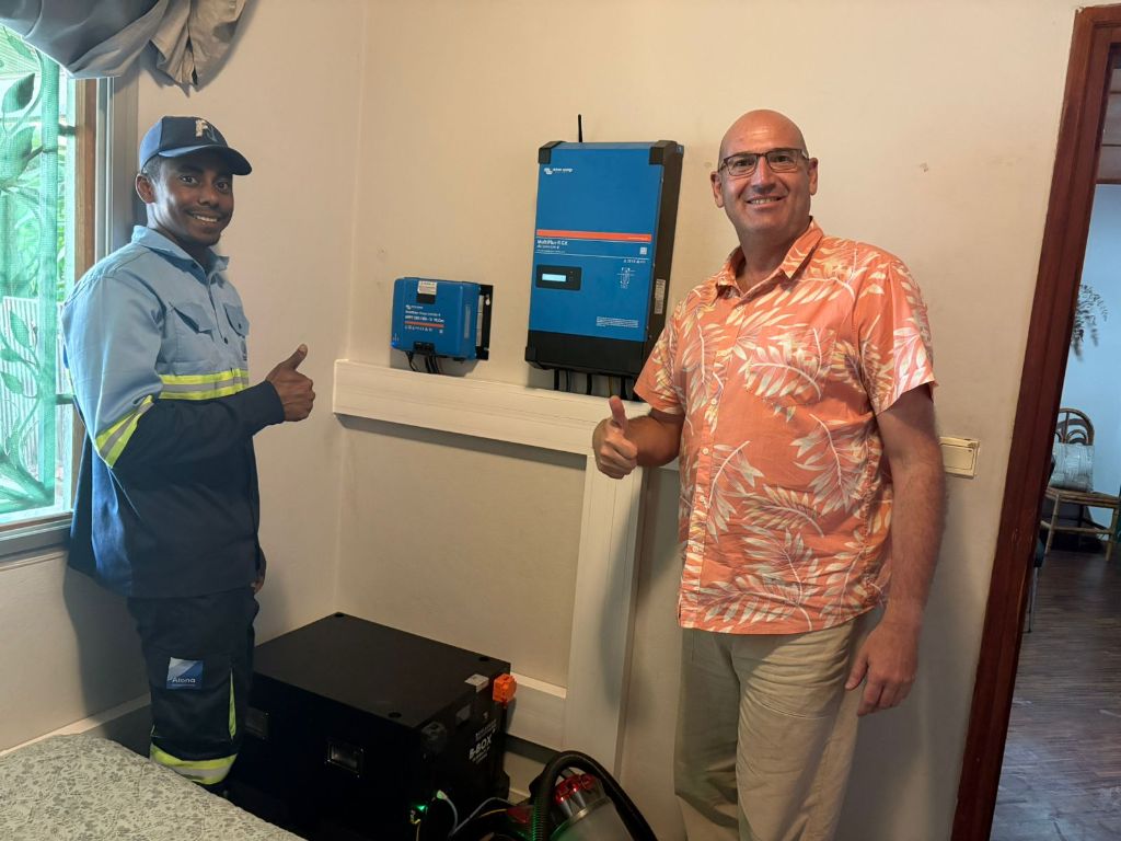 Technicien Alona en uniforme et client satisfait faisant un pouce levé devant installation Victron MultiPlus-II