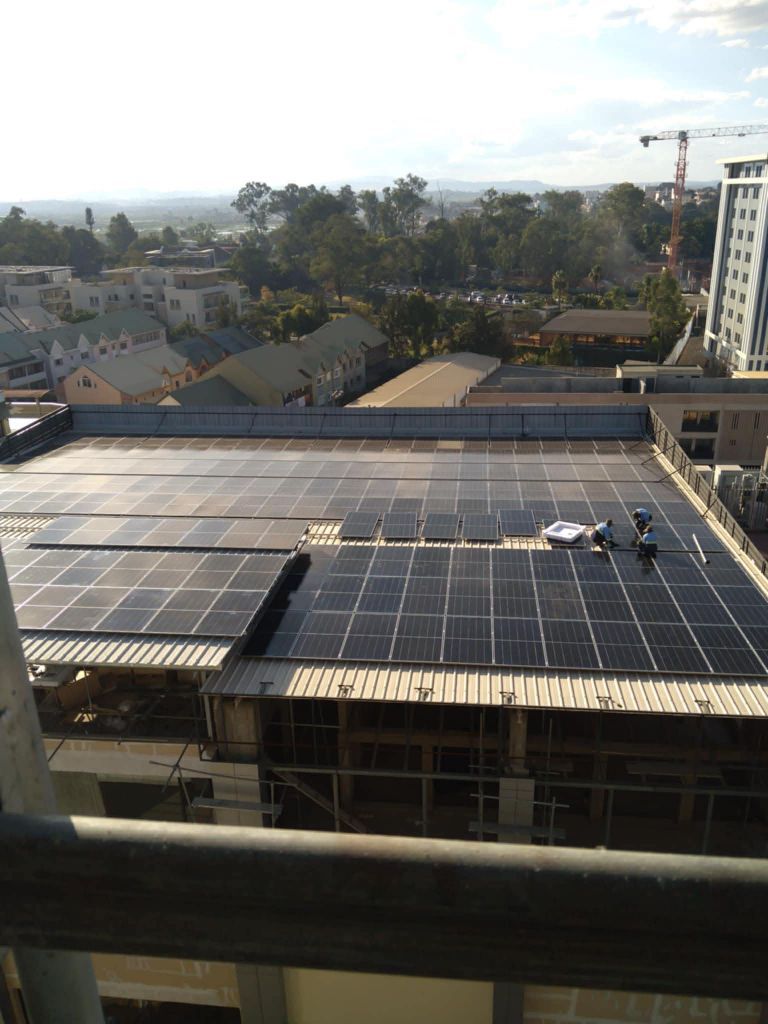 Équipe de techniciens Alona Energy au travail sur grande toiture commerciale Antananarivo